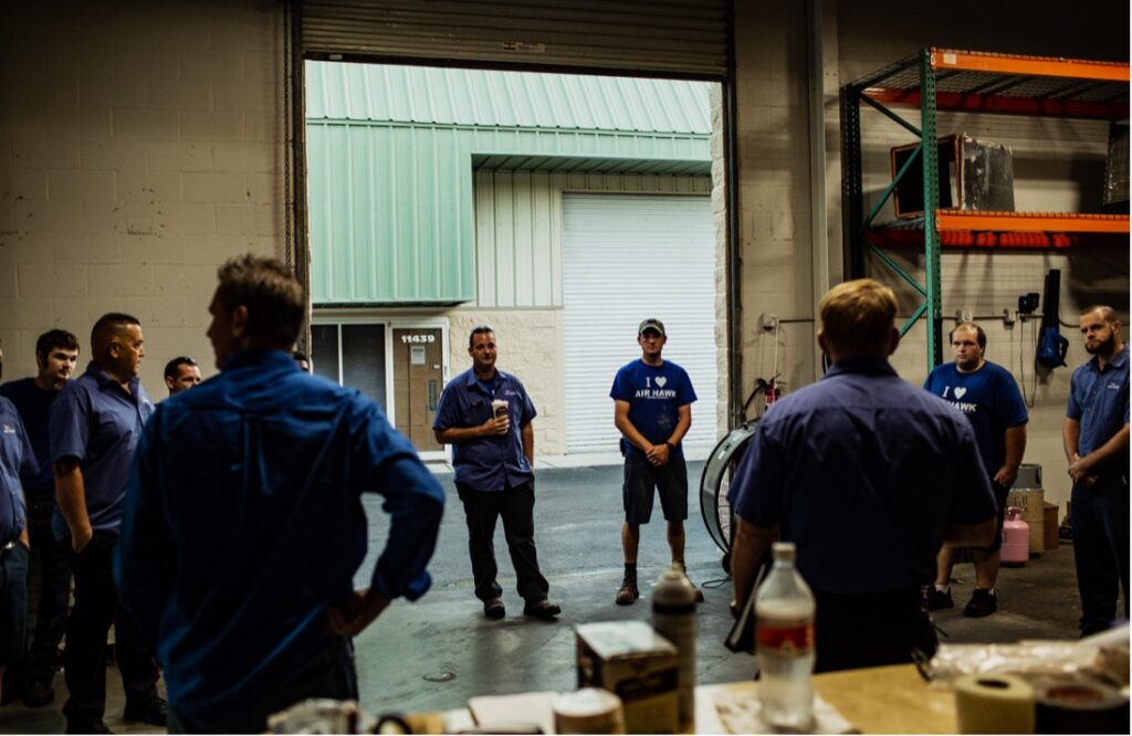 - Housecall Pro HVAC team in huddle at warehouse