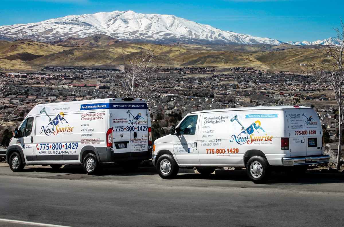 image of two service business trucks on the side of the road with a city behind them
