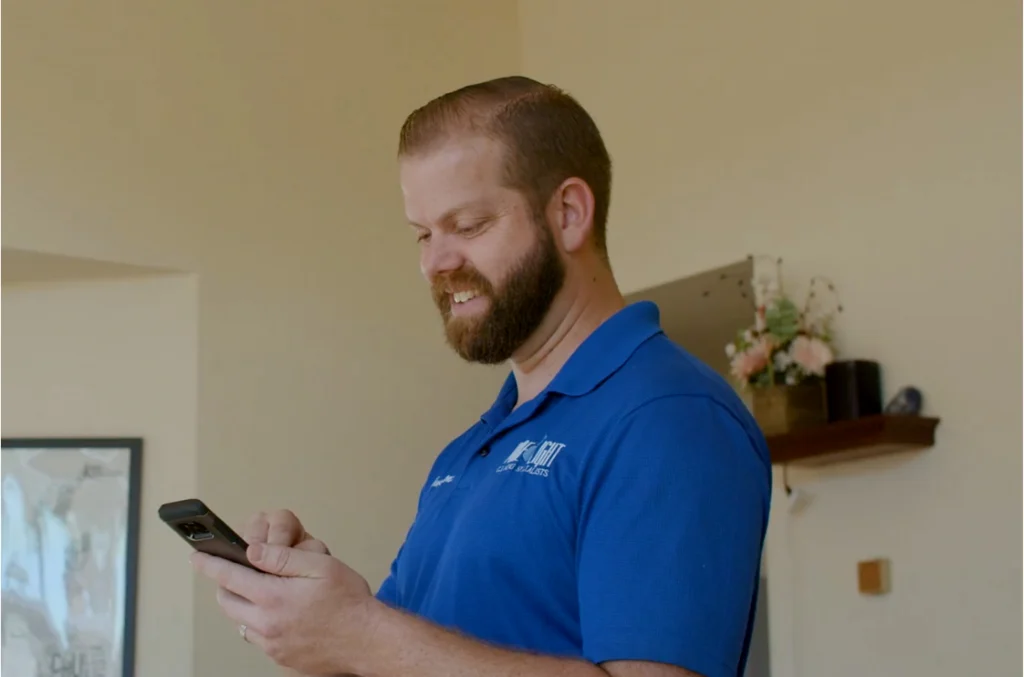 Pro with blue polo smiling while on his mobile phone