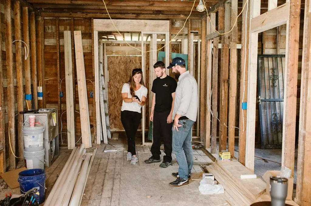 Pros viewing mobile phone inside of wooden framed home