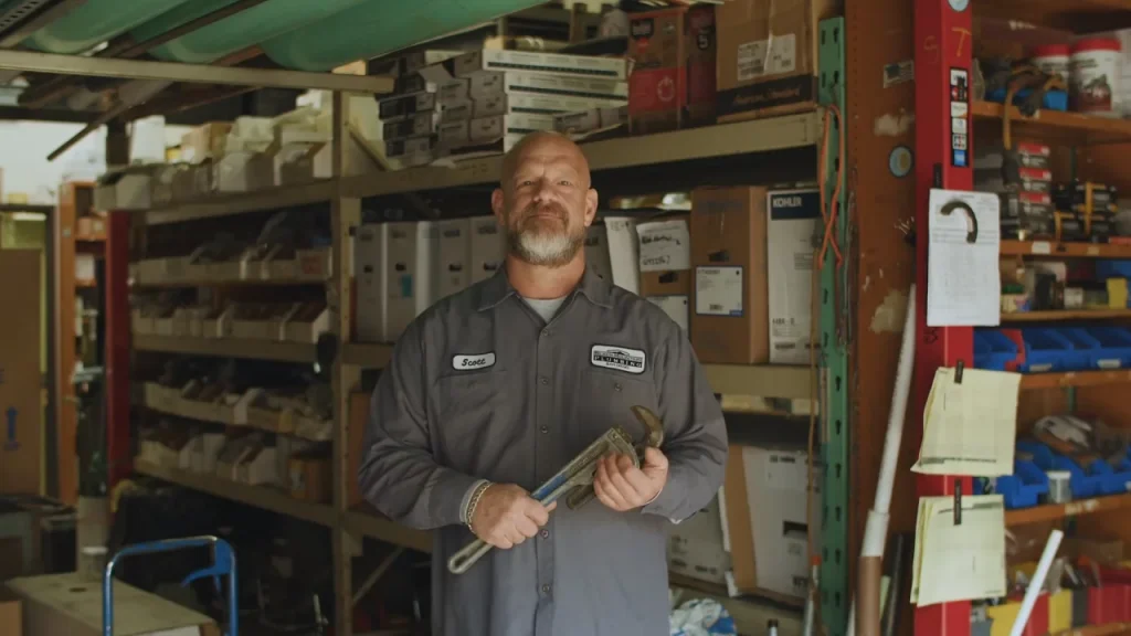 Plumbing pro holds wrench at warehouse