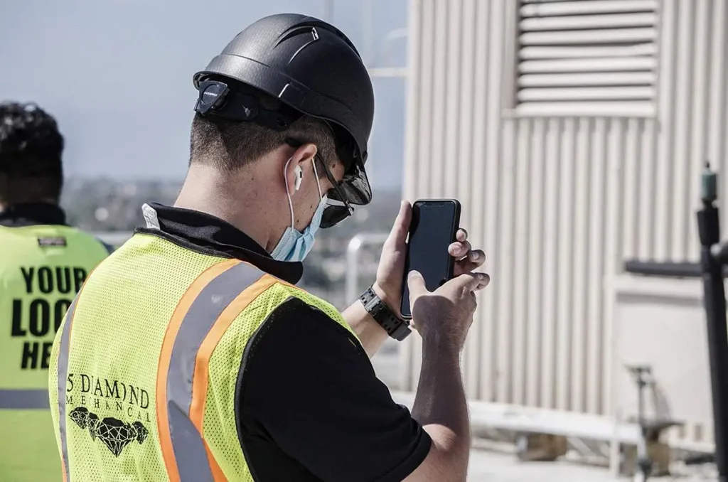 - Housecall Pro HVAC field service technician with black helmet using phone