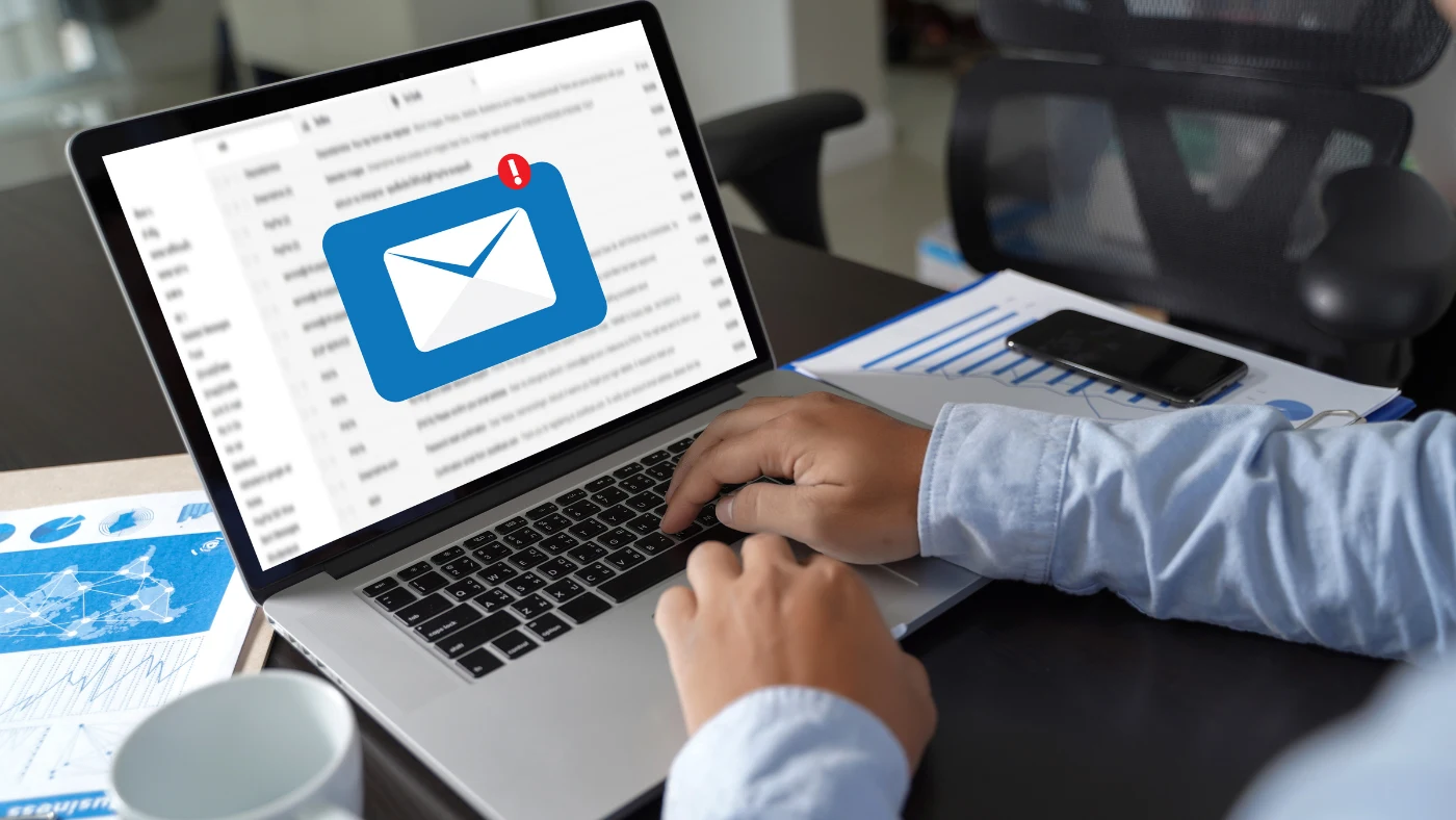 man using email on a laptop while seated at a desk