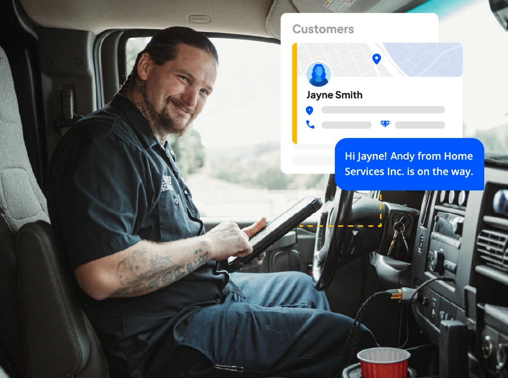 Male electrician on tablet device sits in his work van while smiling at the camera