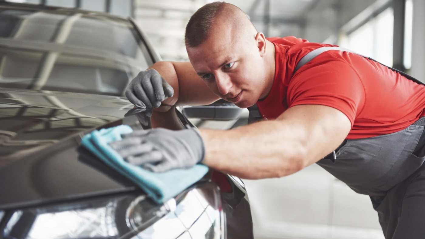pro wiping the exterior of a car with a microfiber cloth