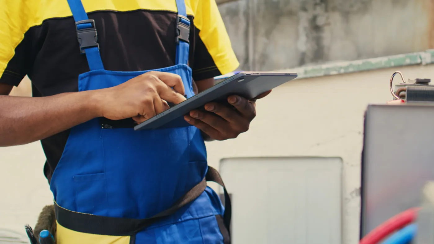 close up of skillful technician commissioned outside for hvac system routine maintenance looking at refrigerant issues using a tablet