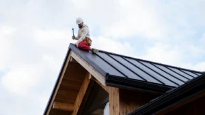 Professional roofer installing black metal roof panels on a residential home.