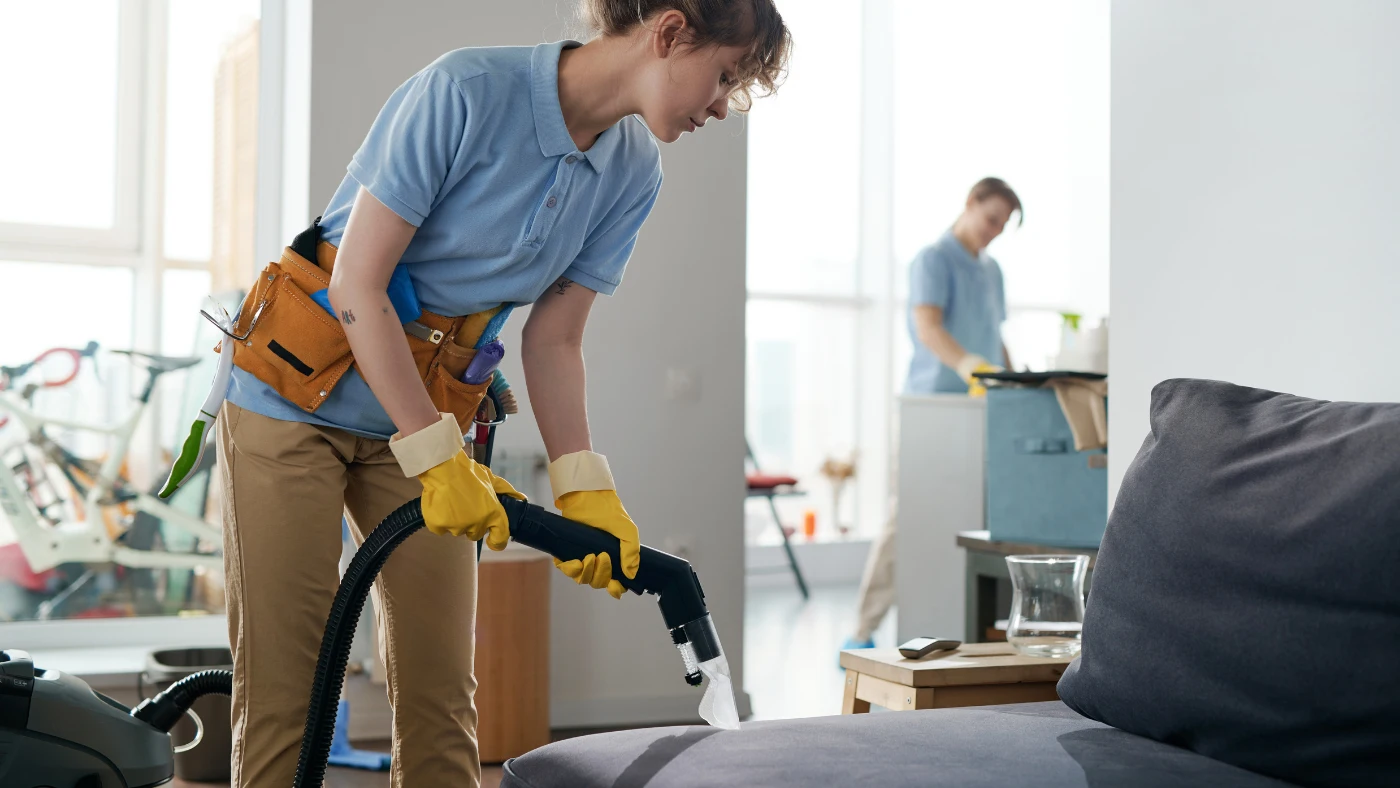 cleaning service workers working in apartment in team, they vacuuming furniture and cleaning the room