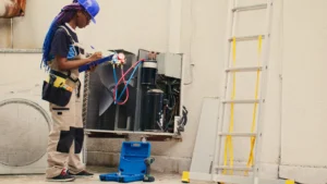 HVAC technician checking an outdoor air conditioning unit with gauges and a service checklist